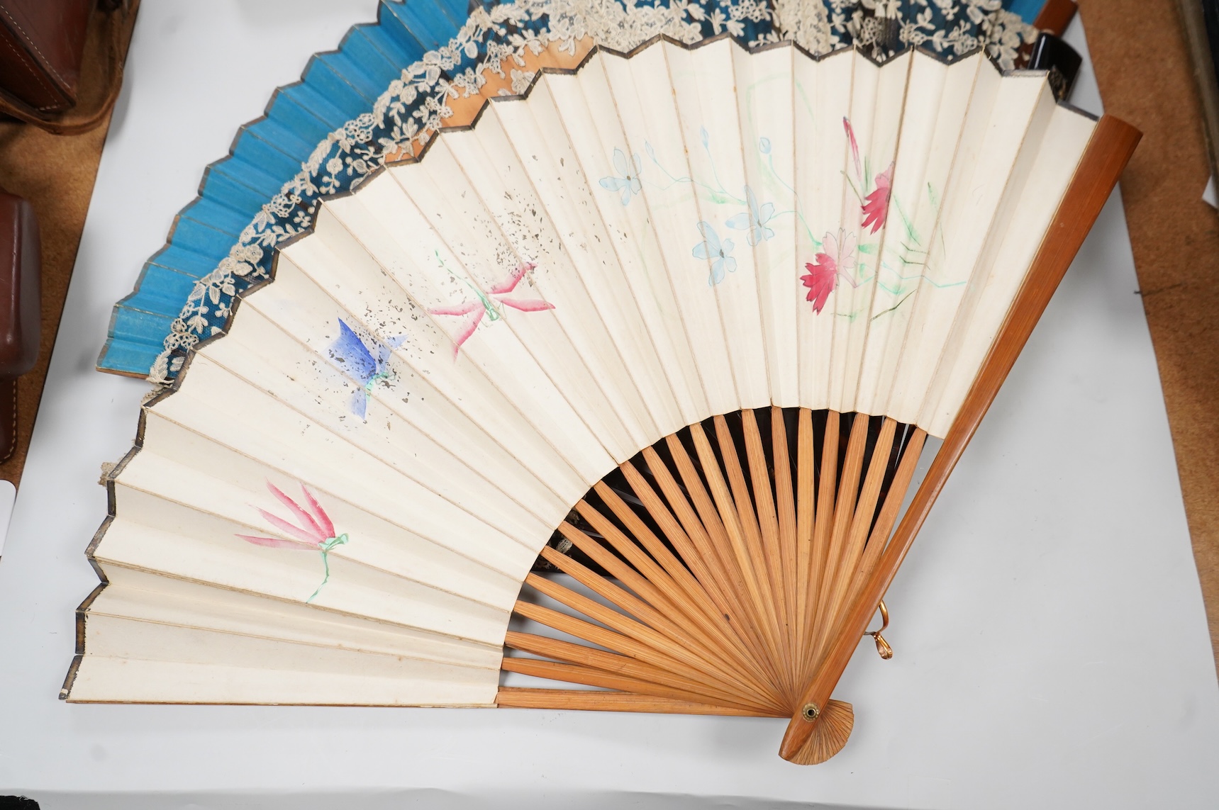 A gold mounted lace and hand painted fan and three others to include a lacquered example, one cased